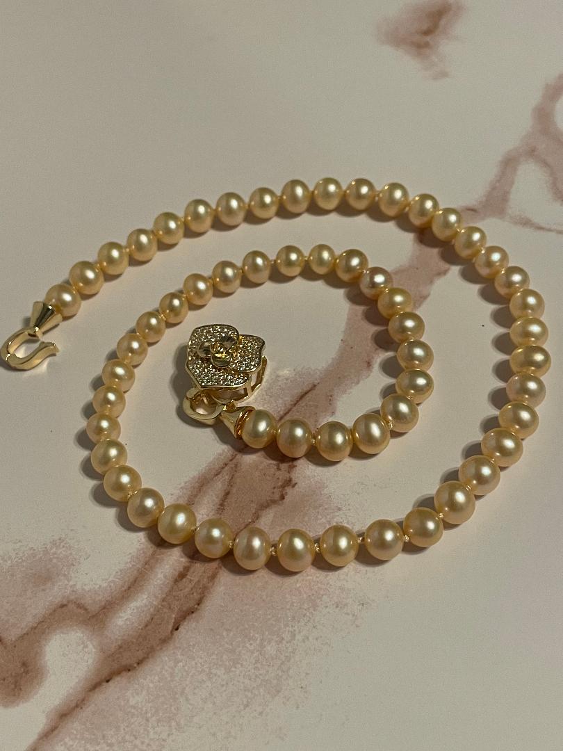 Pearl necklace with a gold clasp on a marble surface